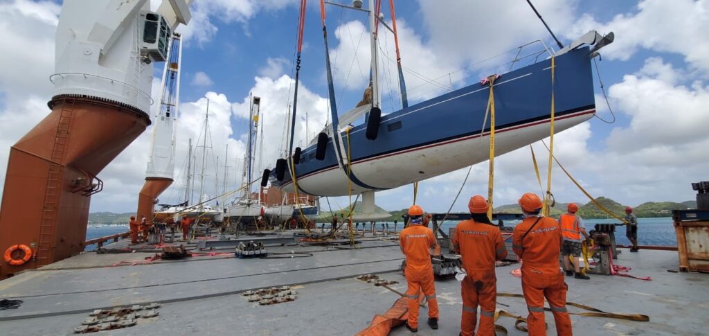On peut voir la rénovation d'un voilier dans un port de construction. 3 personnes